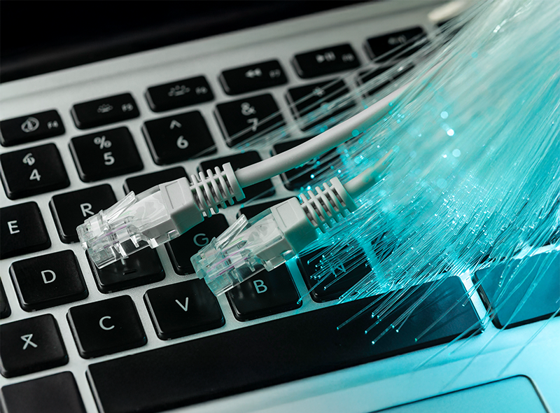 Glasfaserkabeln und Netzwerkkabeln auf einer Laptop-Tastatur